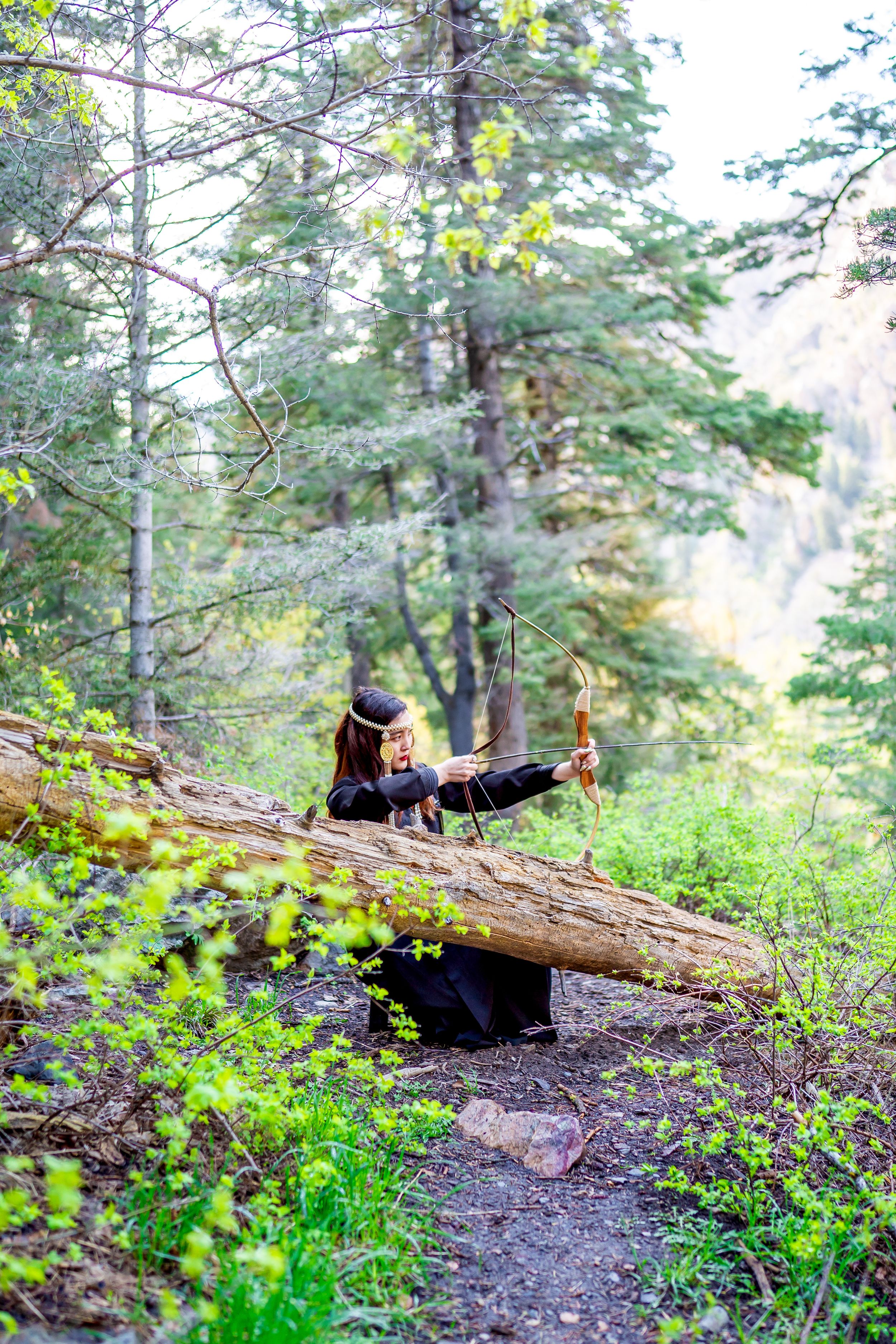 Two people resting on a fallen log while hiking through a lush forest trail.