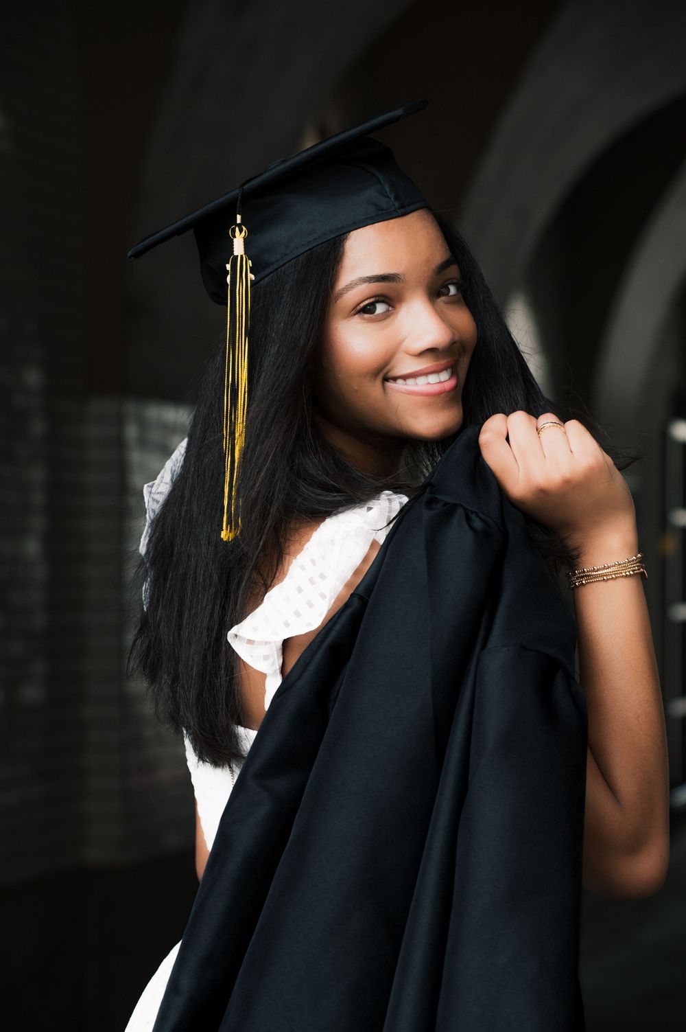 Graduate in black cap and gown poses for professional portraits.