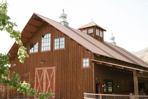 Brown rustic wooden barn with white trim and cupola photographed from multiple angles against blue sky and green foliage.