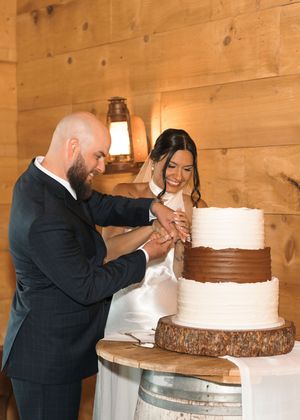 A sequence showing a couple cutting their white wedding cake together at a rustic wooden venue.