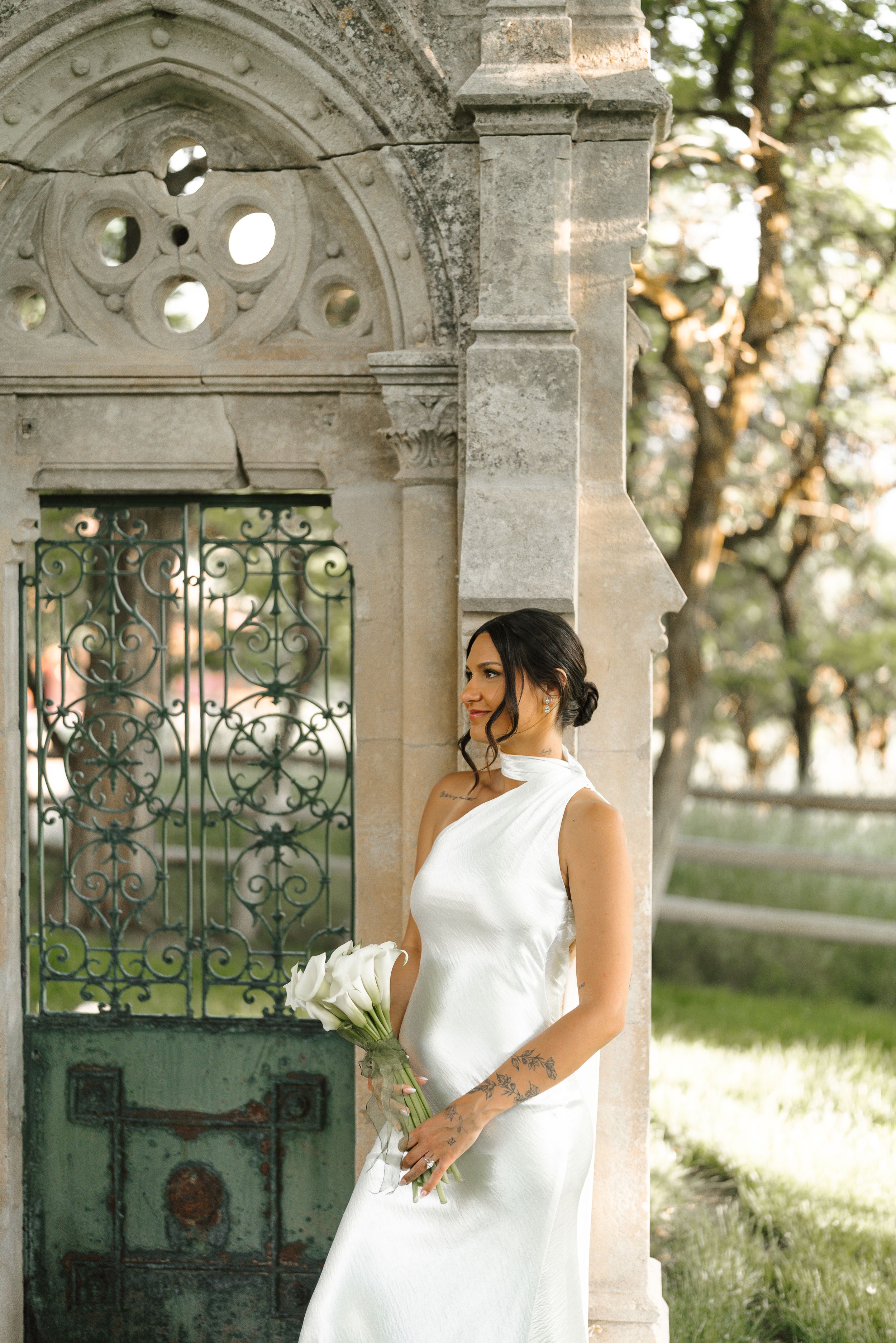 Beautiful stone archway with ornate wrought iron gates creates an elegant outdoor setting during golden hour lighting.