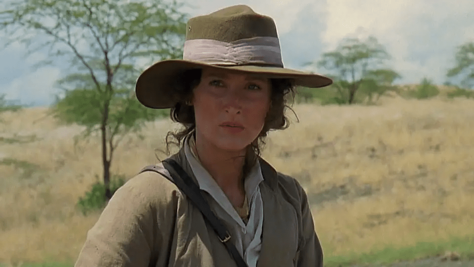 A frontier scene featuring someone in period clothing and a wide-brimmed hat against a dusty landscape.