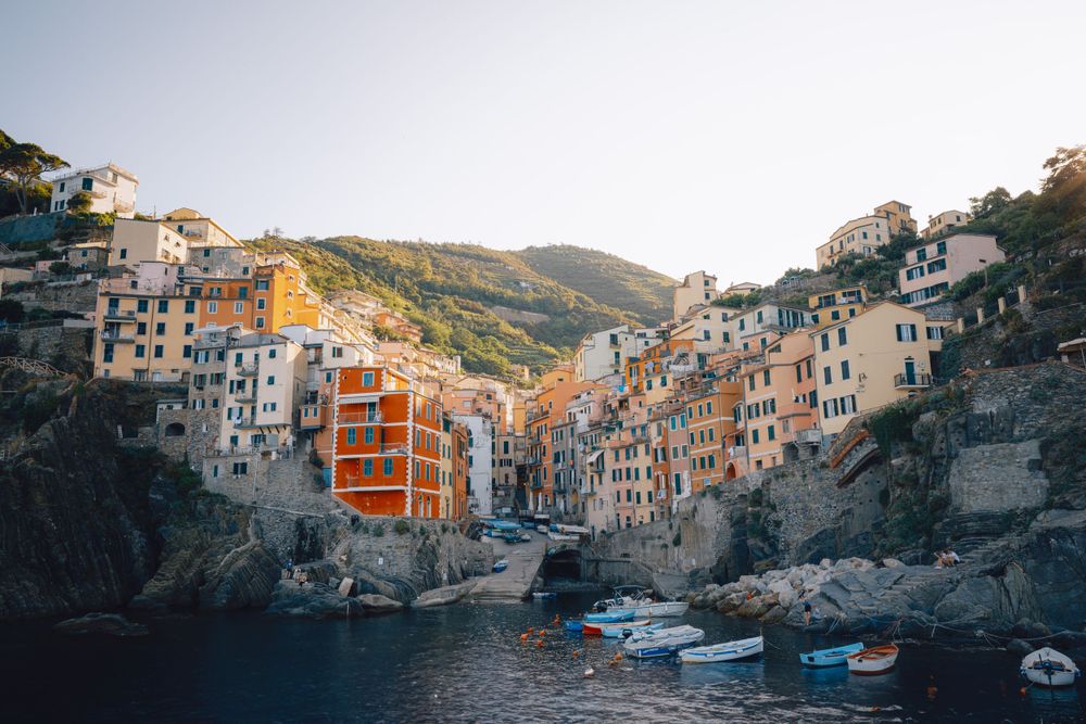 Colorful hillside houses of Riomaggiore in Cinque Terre overlooking boats in the harbor.