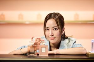 Young Asian woman posing with Chanel Coco Mademoiselle perfume bottles at a beauty counter.