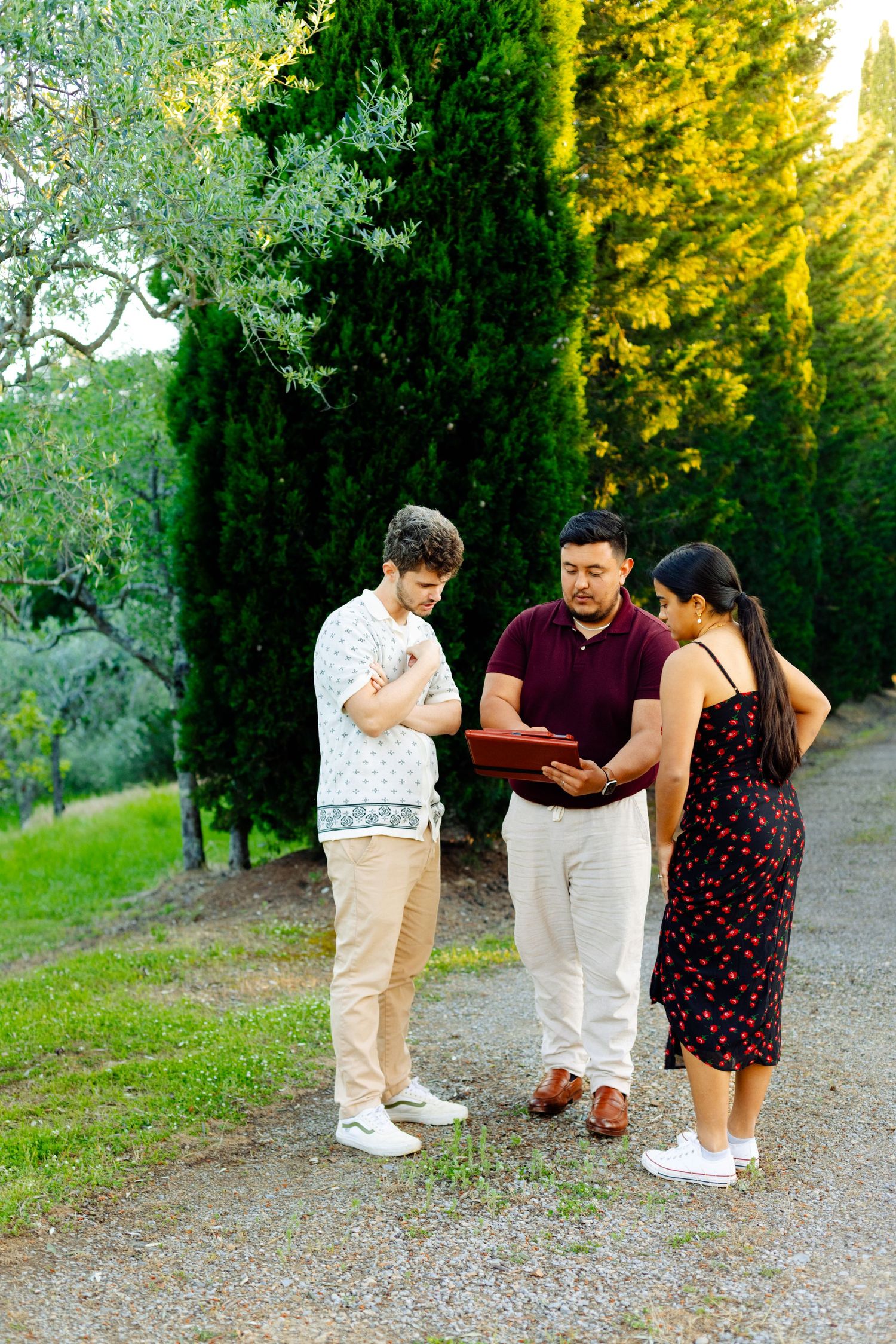 Group looking at document together on path surrounded by cypress trees.
