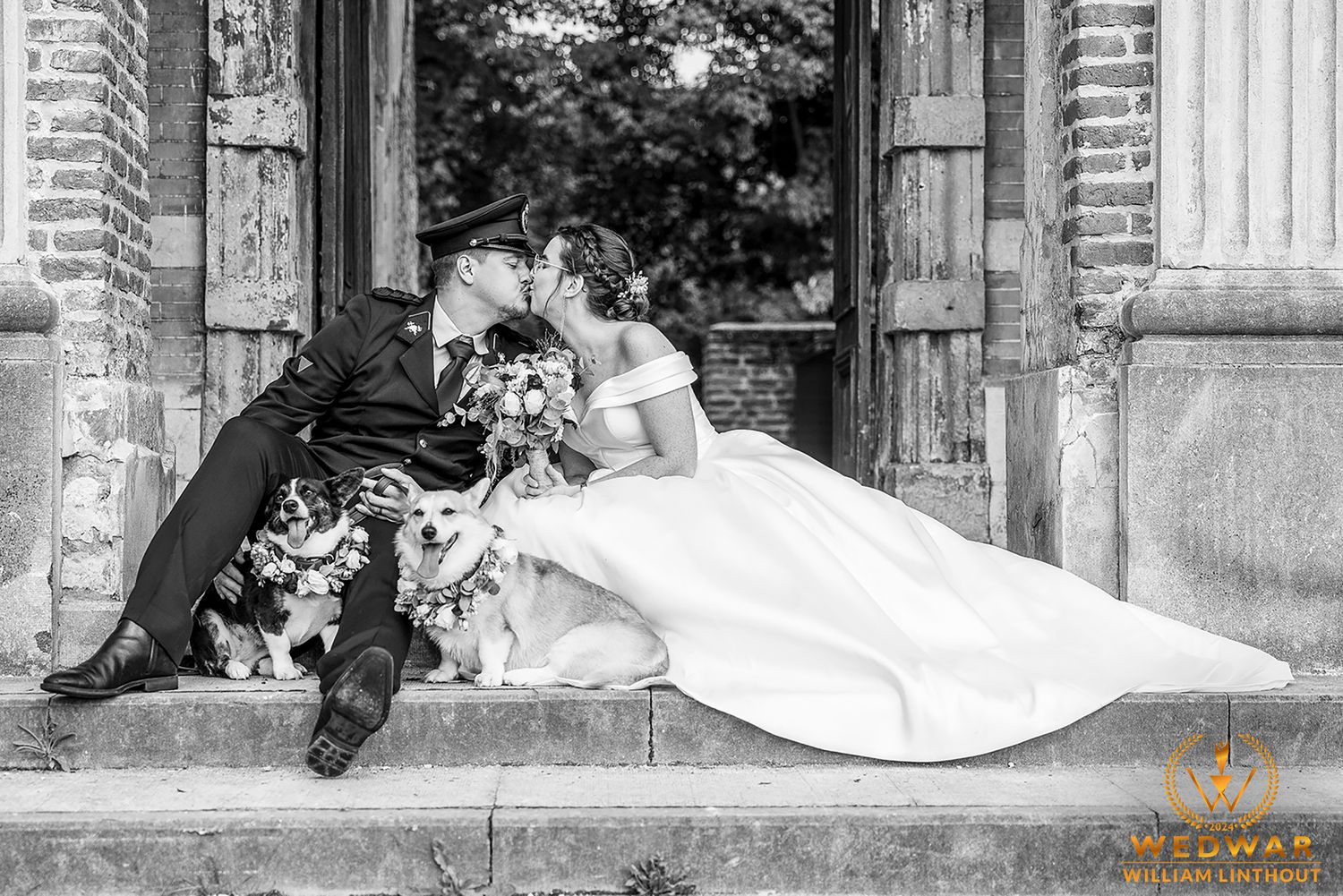 Black and white wedding photo showing a couple sitting on stone steps with flowers in an elegant setting.