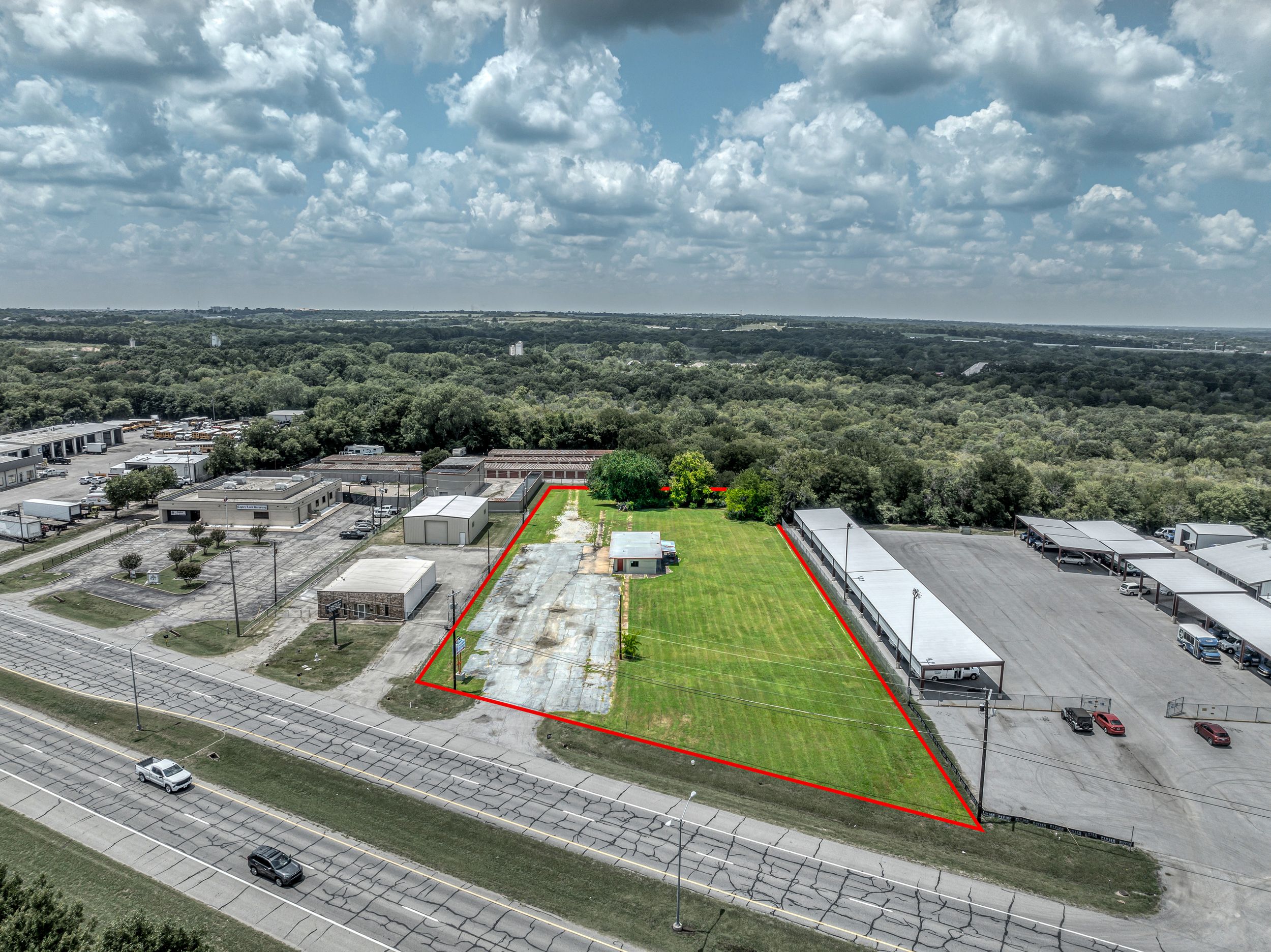 Aerial view of commercial property showing parking lots, green space, and warehouse buildings along a major roadway.