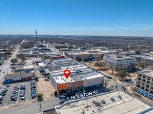 Downtown aerial view showing commercial buildings, parking lots and Houston Street with clear blue skies.