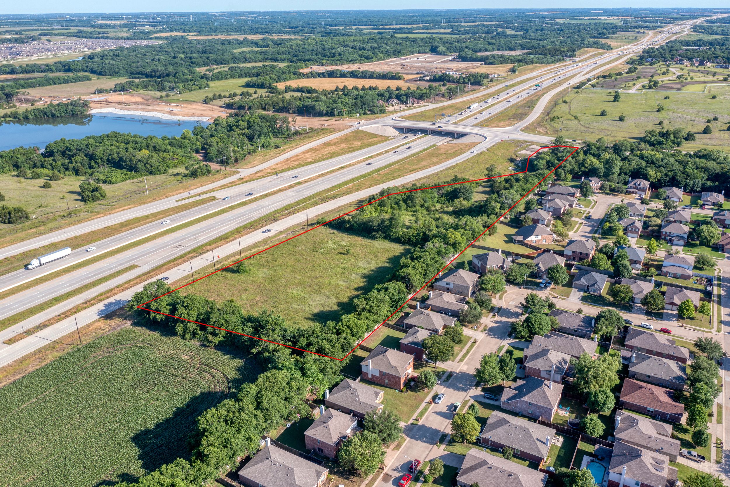 Aerial view of interstate highway intersection with residential subdivision and lake in the background.