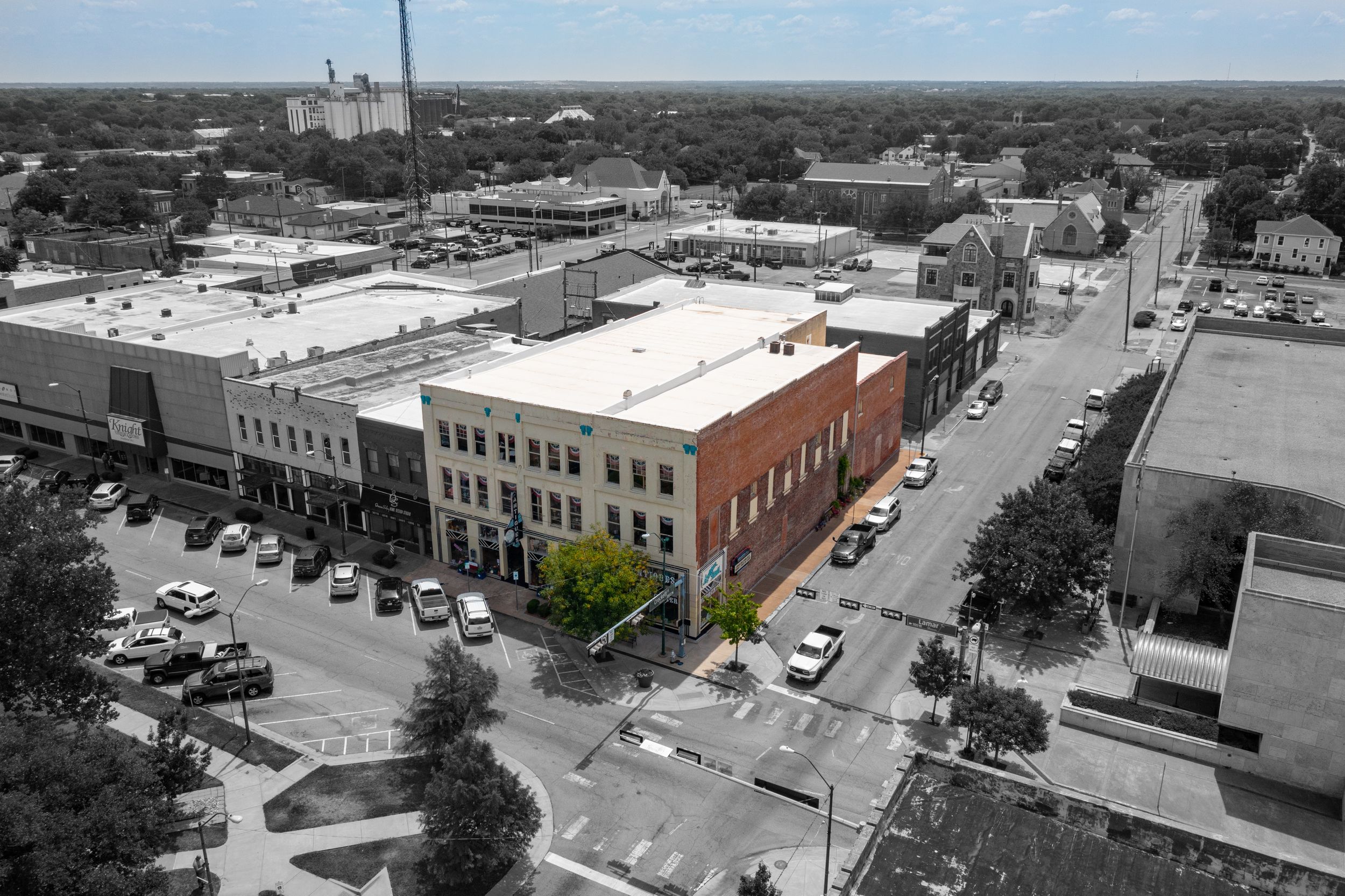 Historic downtown district with vintage brick buildings and parked cars, highlighted in selective color.