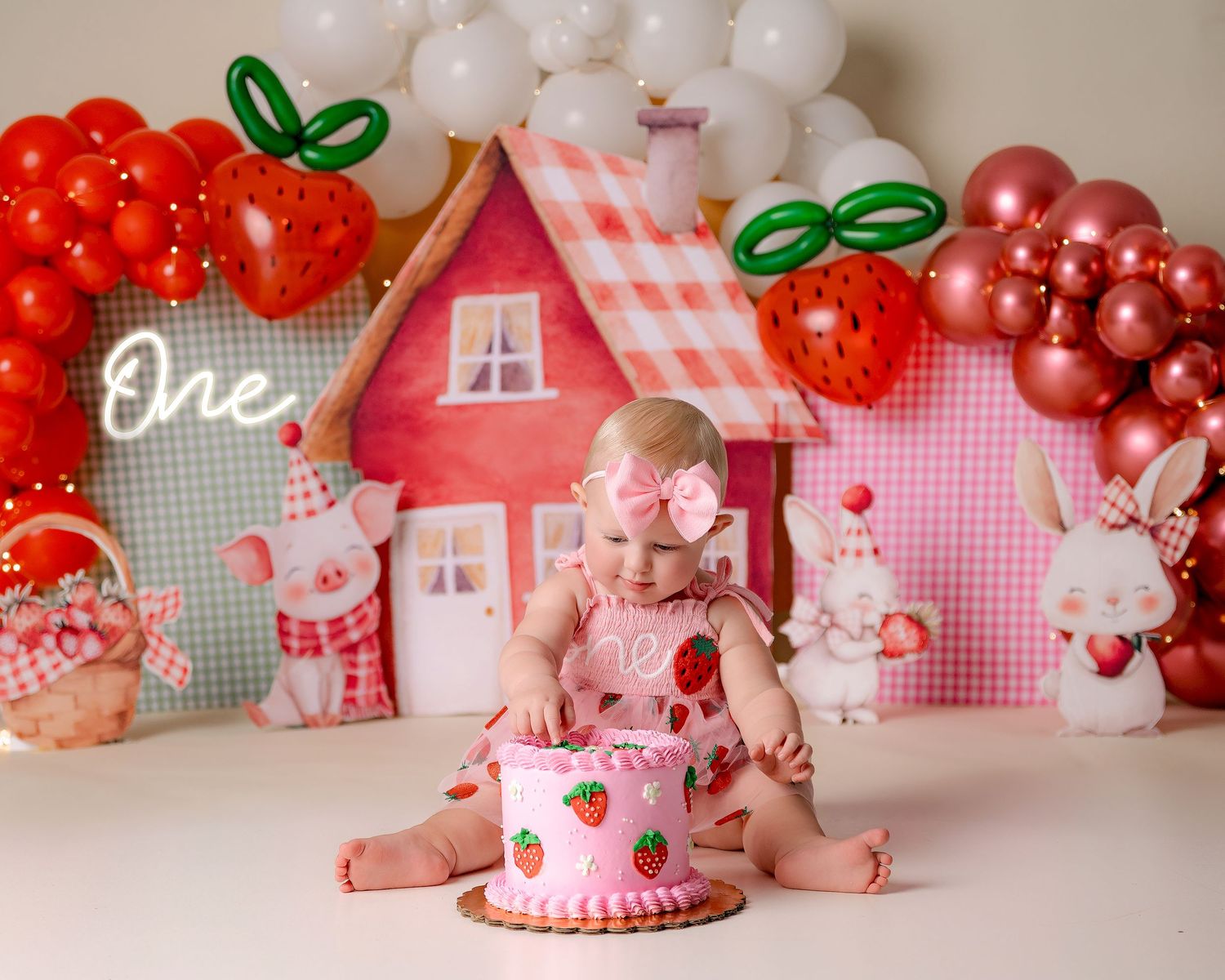 Baby sitting with decorative balloon arch featuring green, gold and white balloons.