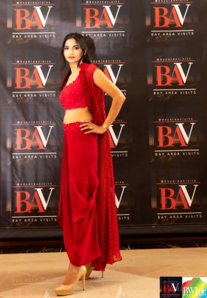 Stunning red two-piece ensemble featured against BayAreaVisits media wall at fashion show.