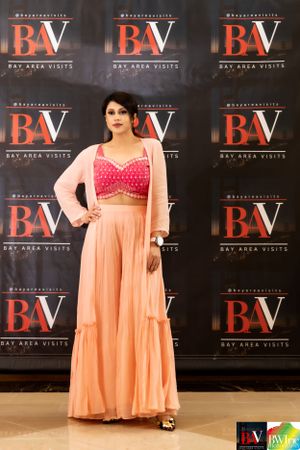 Peach and pink traditional outfit showcased at BayAreaVisits fashion event backdrop.