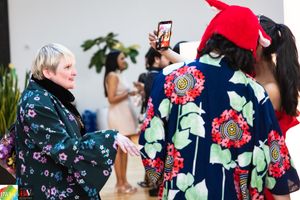 Attendees in colorful floral prints interact at a social gathering.