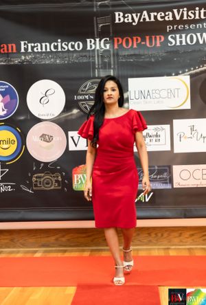 Model walks runway in fitted red dress at San Francisco pop-up fashion show.
