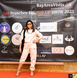 Model poses in casual pink loungewear against branded backdrop at pop-up fashion show.