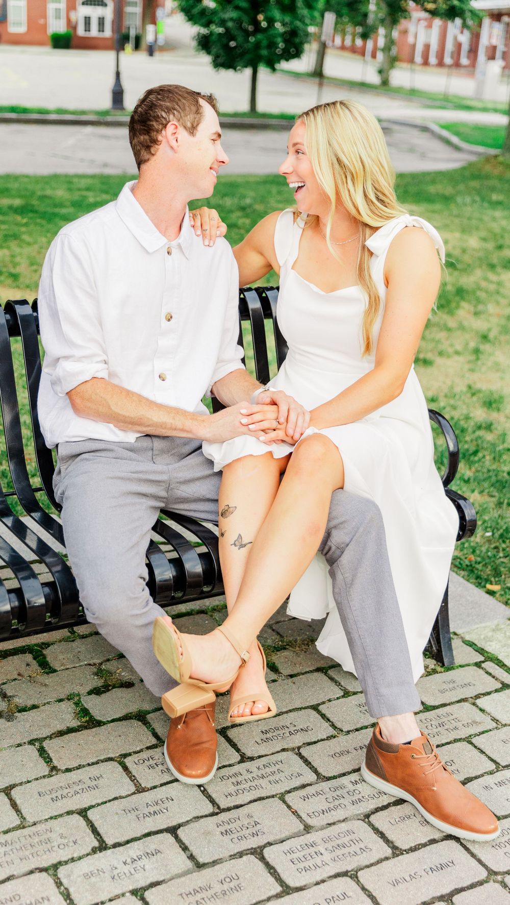 A couple shares a joyful moment while sitting on a park bench.