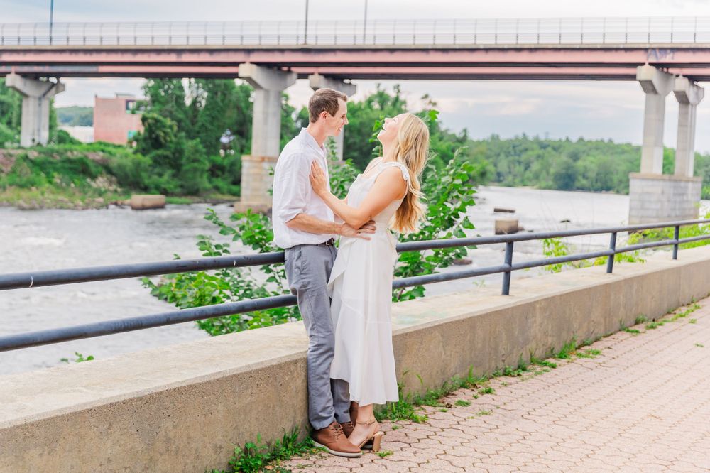 A couple in summer attire stands along a riverside walkway.