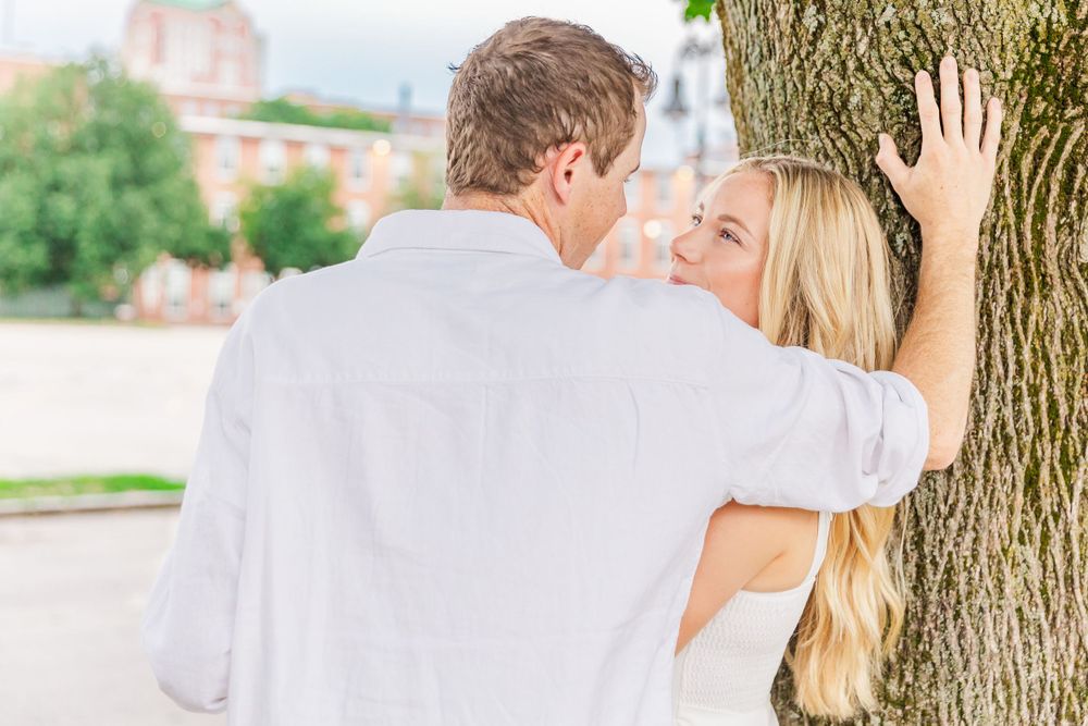 A romantic moment captured between a couple against a tree trunk.