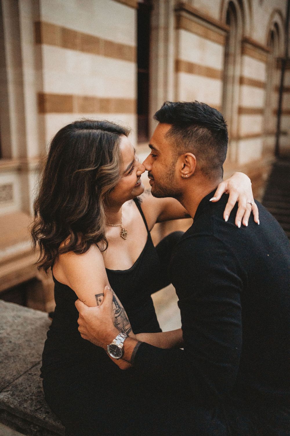 An intimate embrace captured against warm-toned architectural details at sunset.