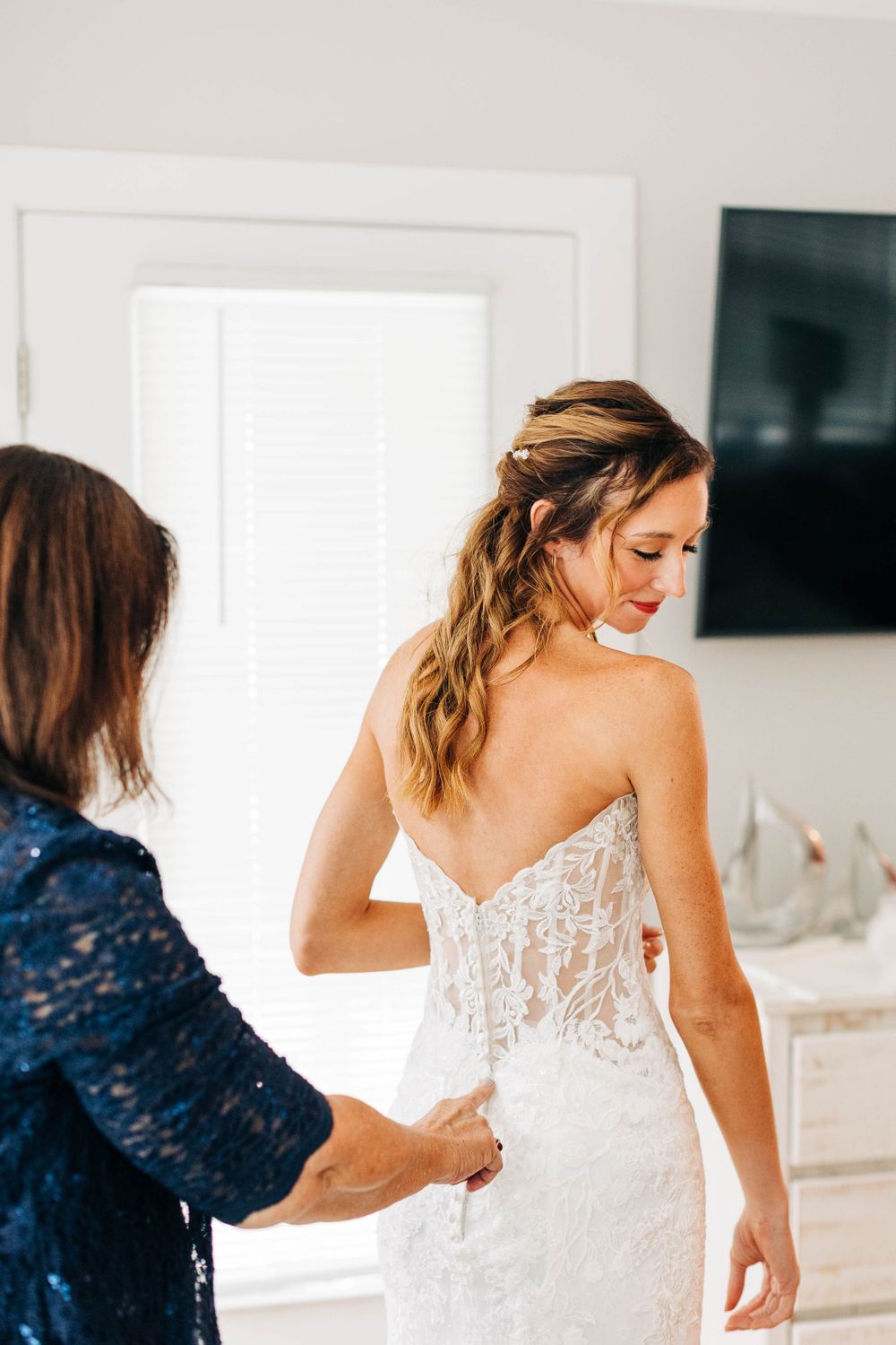 Wedding dress fitting moment as final adjustments are made to a lace gown.