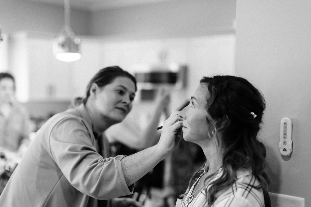 Wedding preparation scene with makeup artist working on bride's face.