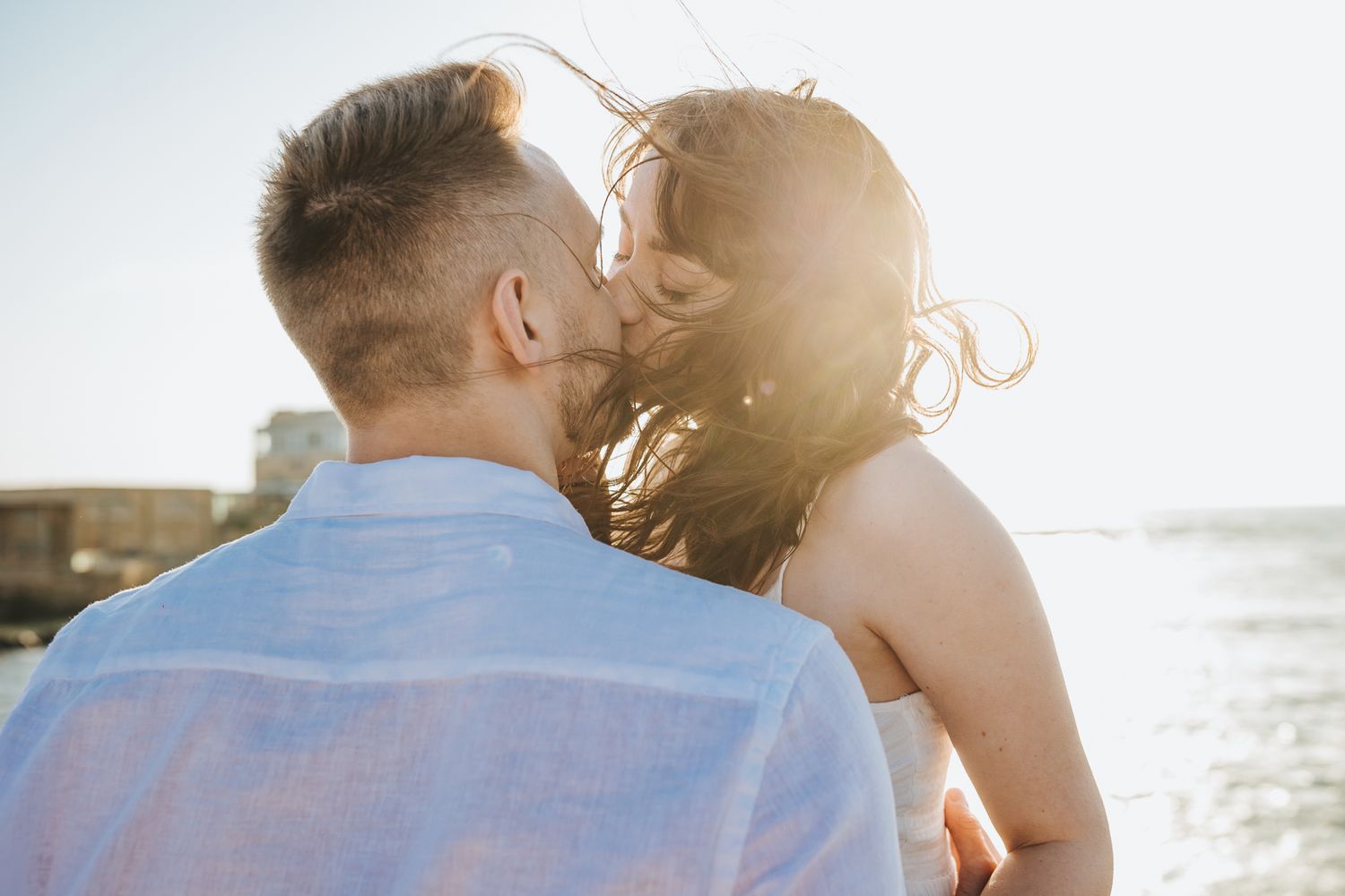 Sunlit couple sharing tender moment at beach during golden hour.