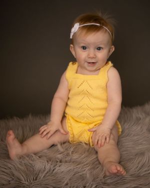 A baby girl sits up straight