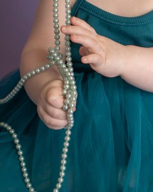 Baby hands play with faux pearls
