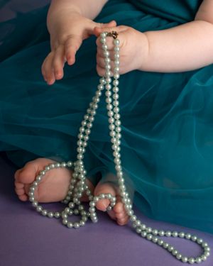 Baby hands and feet play with costume pearls