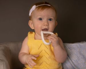 A baby girl brings a toy to her mouth