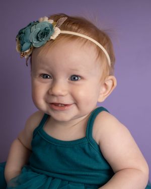 A baby girl grins at something outside of the frame