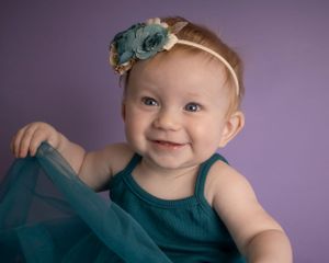 A baby girl plays with her dress