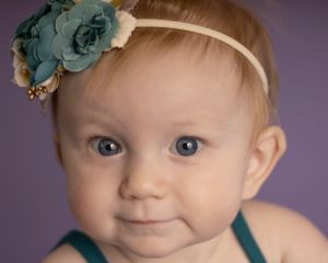 A baby girl looks directly at the camera with a small smile