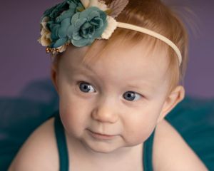A baby girl looks to the side while crawling toward the camera