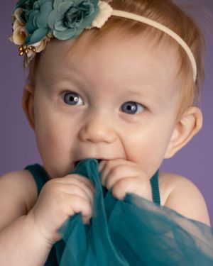 A baby girl chews on her dress/skirt