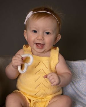 An excited baby holds a heart shaped toy