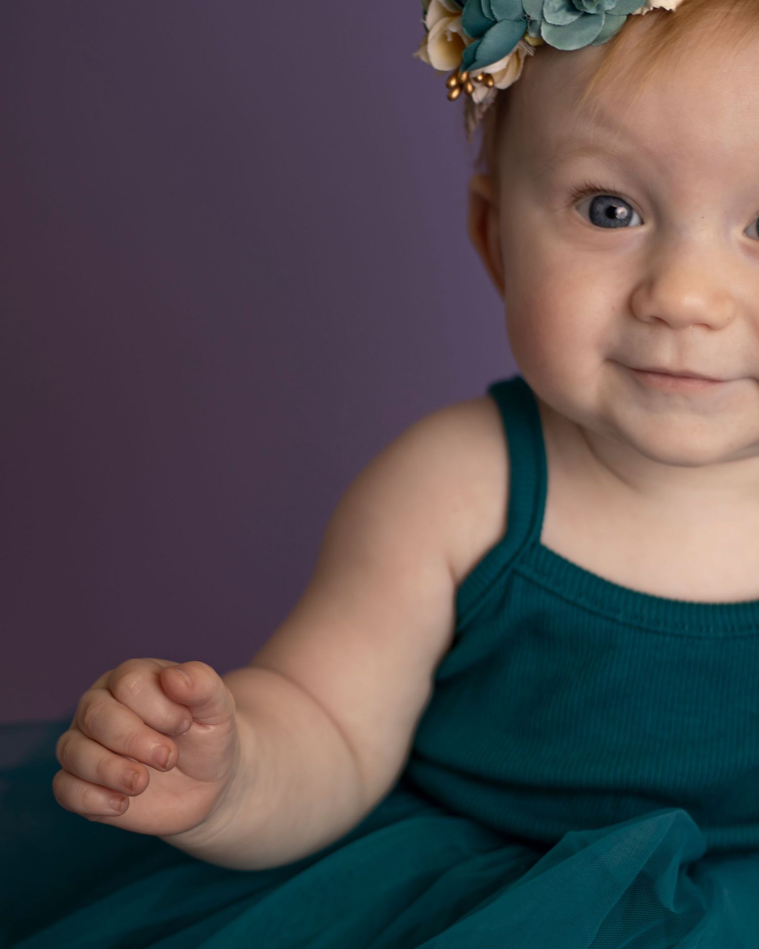 A baby girl looks at the camera, she is off center and only half of her is visible