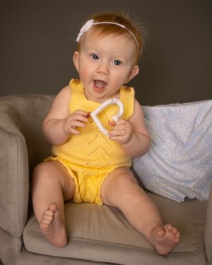 A baby girl holds a heart shaped teether