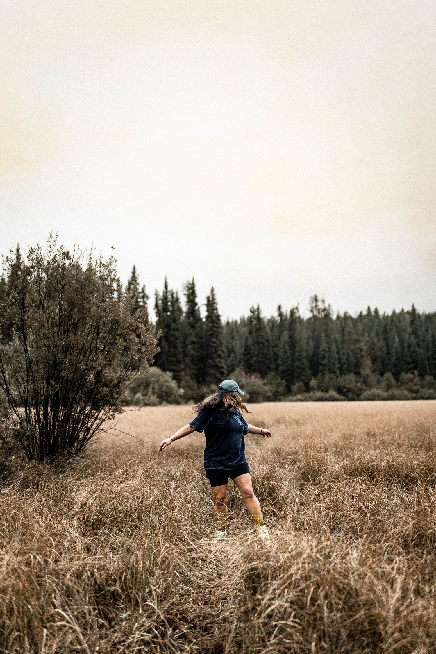 A sequence of candid lifestyle photographs showing a person running through a golden autumn meadow with evergreen trees in background.