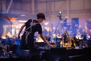 waiter serves at an awards ceremony with blue lighting and fog effects.
