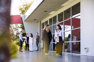 workers attending a conference gather outside a modern building during a break on a sunny day.