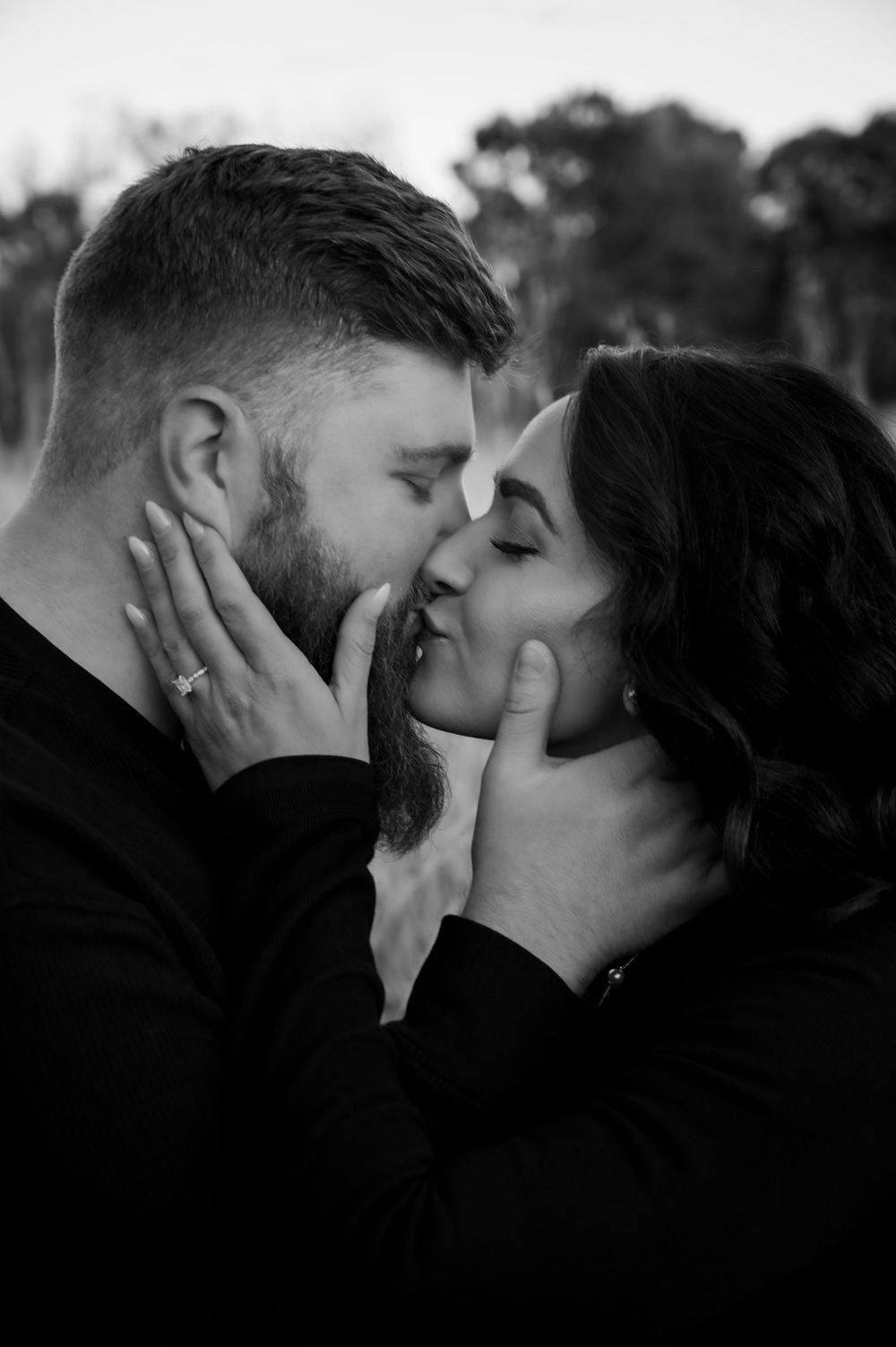 Black and white romantic couple almost kissing, tenderly holding each other's faces.