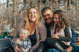 Laughing family of four enjoying a festive outdoor portrait session in a winter setting.