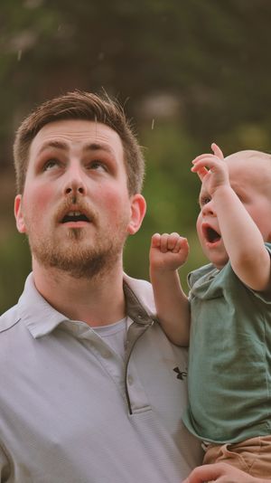 Father and excited toddler boy looking up together outdoors in nature.