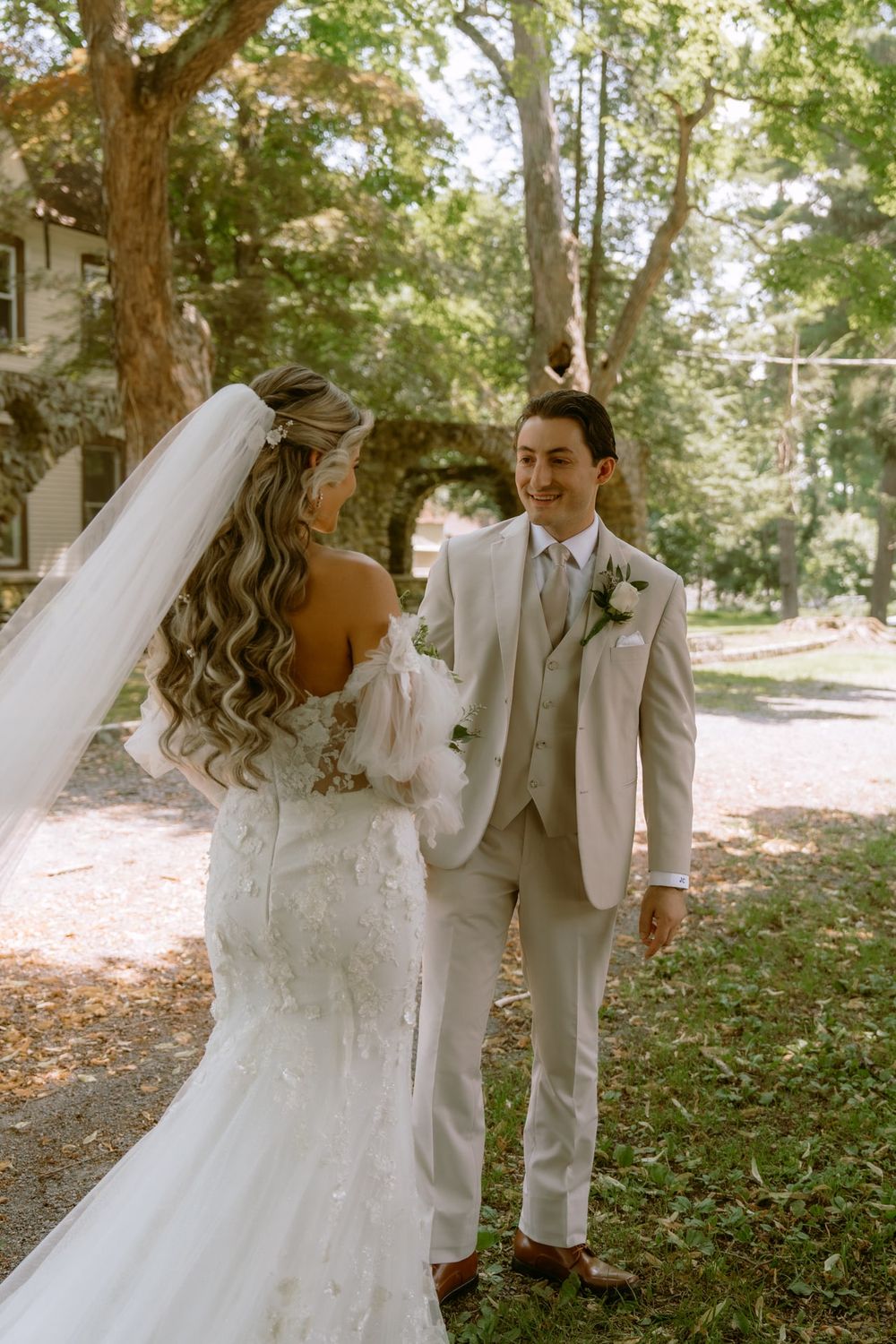 A couple shares their first look moment in a sunlit garden setting on their wedding day.