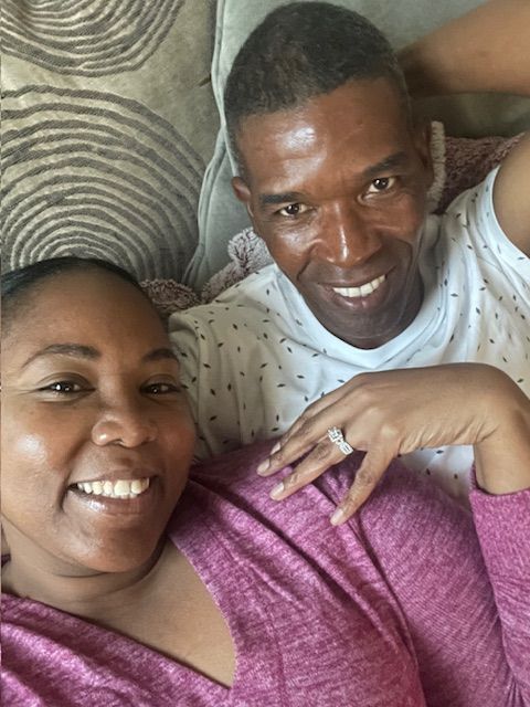 A cozy selfie of a couple relaxing together and smiling at the camera.