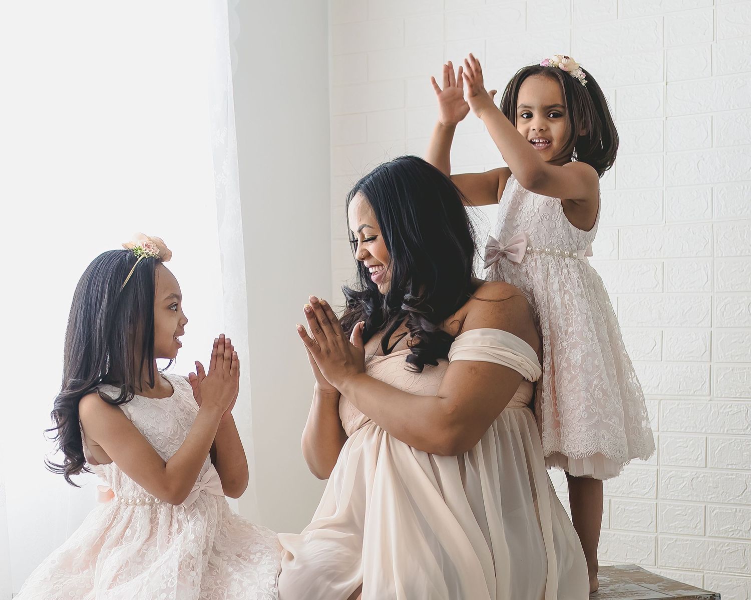 Candid family moment showing joyful expressions and playful interaction in white dresses.
