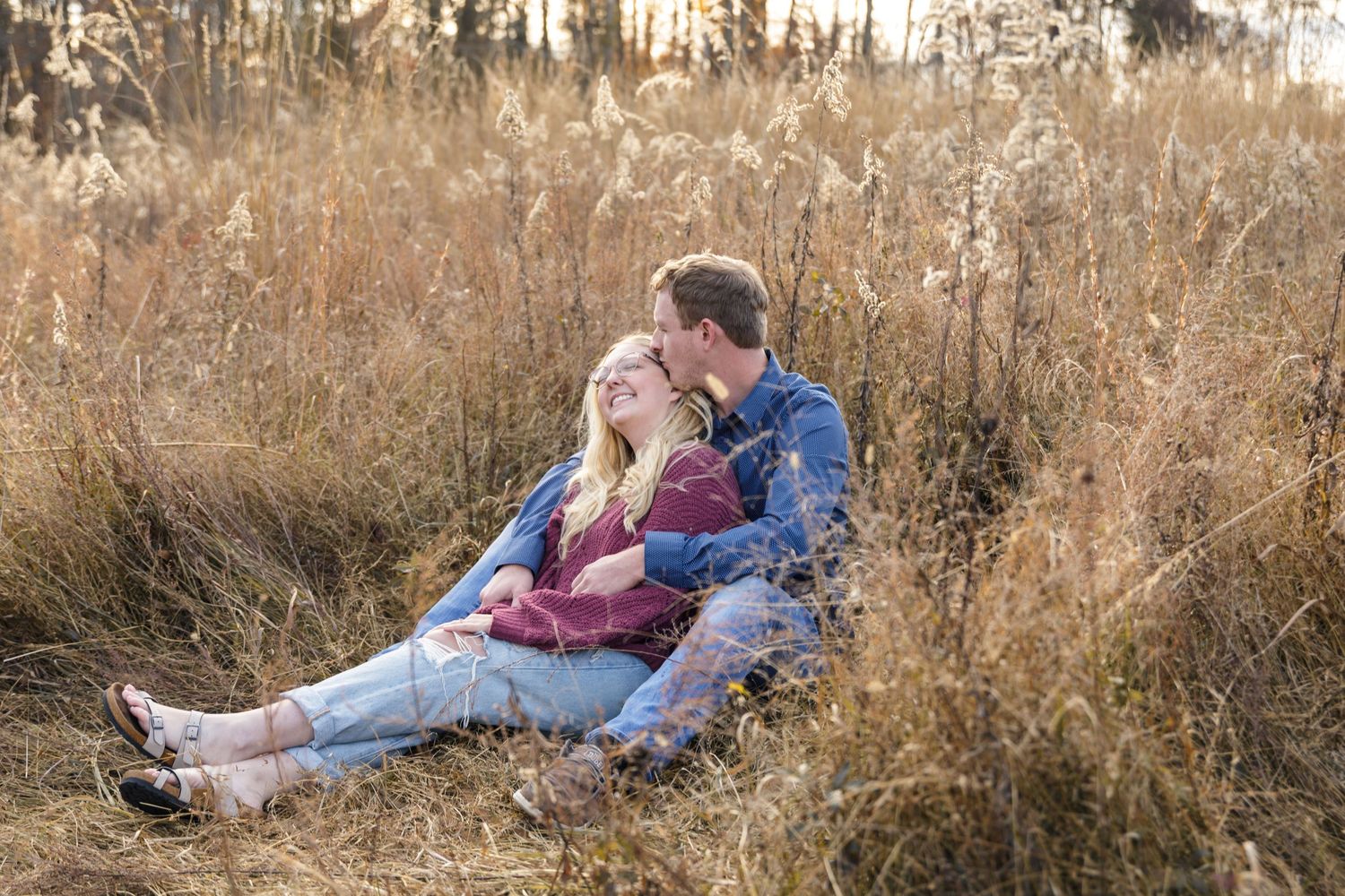 A couple shares an intimate moment together in a field of tall autumn grass.