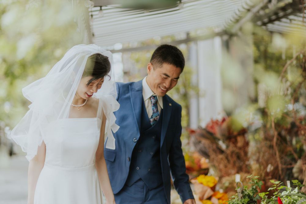 A couple shares an intimate moment among colorful flowers at their wedding.